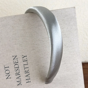 Close-up of padded silver-grey satin headband showing shimmering fabric and silky texture