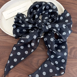 Close-up of brown polka dot silk scarf with elegant wave pattern on a white plate