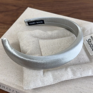 Close-up of silver-grey satin headband featuring a hand made woven label and silky texture