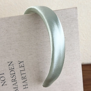 Detail of light green satin headband with pearlescent finish on a vintage book