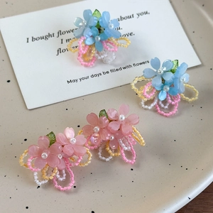Détail de boucles d'oreilles fleurs en perles roses faites main sur plateau céramique