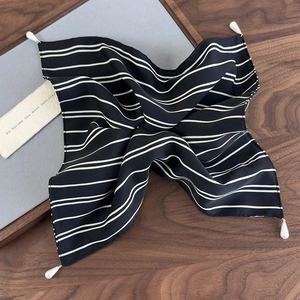 Detailaufnahme des eleganten schwarzen Seidenschals mit Streifen und weißen Perlenanhängern