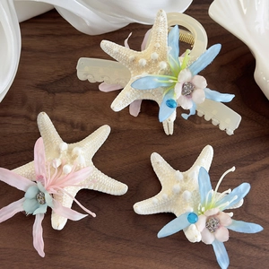 Ocean starfish hair clips set with artificial flowers on dark wood background