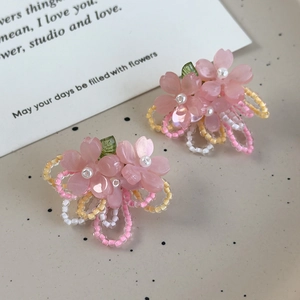 Détail de boucles d'oreilles fleur de cerisier avec perles roses et pétales en résine douce