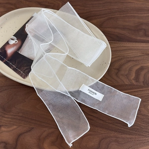 Détail de ruban en organza blanc avec étiquette sur un plateau en céramique