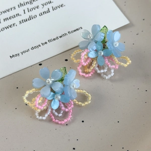 Gros plan de boucles d'oreilles fleurs bleues faites à la main avec perles roses