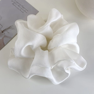 Close-up detail of oversized white organza scrunchie with soft pleated texture and sheen