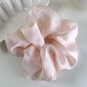 Macro detail of oversized organza scrunchie with a shimmering pearlescent satin texture
