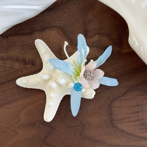 Detailed close-up of a sea star hair clip with blue silk flowers and glittery accents