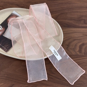 Détail d'un ruban en organza rose avec étiquette qualité sur une plaque en céramique