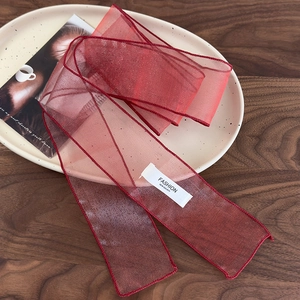 Détail d'un ruban en organza bordeaux avec étiquette sur un plateau en céramique