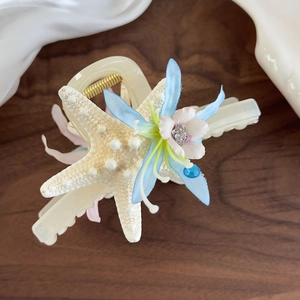 Detail of starfish hair claw clip with blue fabric flowers and golden metal spring