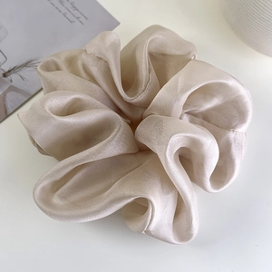 Macro detail of oversized champagne organza scrunchie with elegant pleated fabric texture