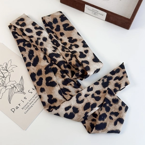 Detailed view of elegant leopard print silk scarf on a white desk with French cards