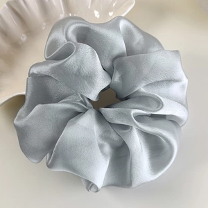 Macro shot of oversized organza scrunchie in light blue on a decorative white dish