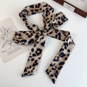 Macro shot of a silky leopard print scarf tied in a knot on a white minimalist background