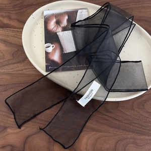 Détail d'un foulard en organza noir transparent avec étiquette de mode et ourlet roulé