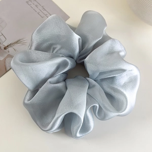 Close-up of light blue oversized organza scrunchie with silky satin texture and pleats