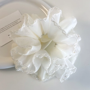 Vue détaillée d'un grand chouchou blanc en organza avec broderie de bord ondulé