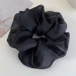Macro detail of oversized black organza scrunchie with silky texture and soft folds
