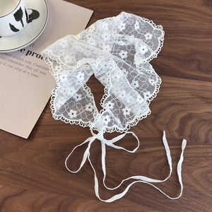 Close-up of white floral lace scarf belt with scalloped edges and ties on wood