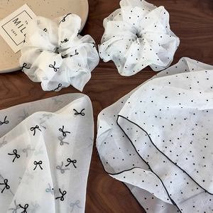 Lot de chouchous en organza blanc avec pois noirs et nœud sur table en bois