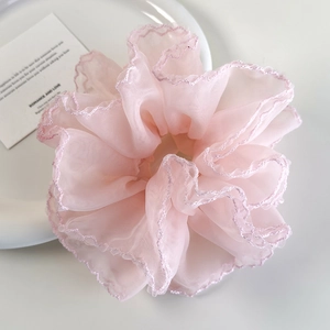Vue détaillée du chouchou en organza rose à volants sur une assiette en céramique blanche