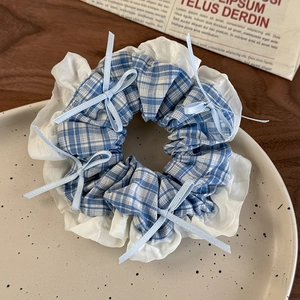 Detail of blue plaid hair scrunchie with white lace trim and small ribbon bows