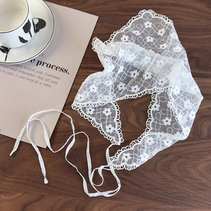 Close-up of white floral lace triangle headscarf with scalloped edges on a wooden table