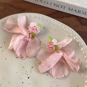 Gros plan détaillé de boucles d'oreilles pétales en mousseline rose avec perles