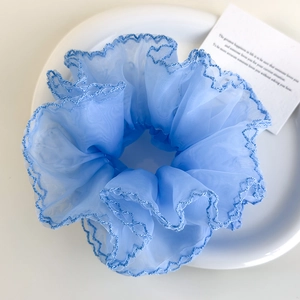 Gros plan du chouchou en organza bleu clair avec broderie sur une assiette blanche