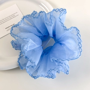 Détail d'un chouchou en organza bleu ciel avec des coutures en zigzag bleu foncé sur le bord