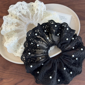 Chouchous élégants en dentelle blanche et noire avec perles sur une table en bois