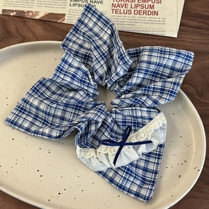Detail of blue plaid scrunchie with lace edge and ribbon bow on a ceramic tray