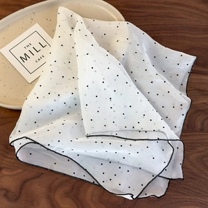 Détail du foulard à cheveux en mousseline blanche à pois avec bordure noire et texture douce