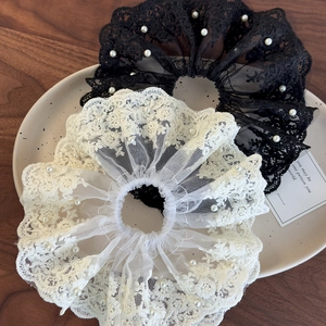 Set de chouchous en dentelle française avec perles noires et blanches sur plat céramique