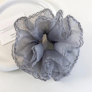 Vue détaillée du grand chouchou en organza gris clair avec bords ondulés argentés