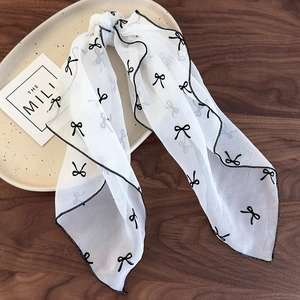 Détail d'un chouchou en mousseline blanche avec imprimé nœuds noirs et couture fine