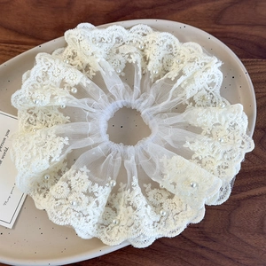 Détail d'un chouchou en dentelle blanc crème avec broderie et perles d'imitation