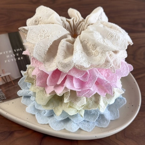 Pastel lace hair scrunchies with floral embroidery displayed on a white plate