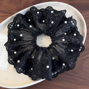 Détail du chouchou en dentelle noire avec perles blanches sur plateau vintage