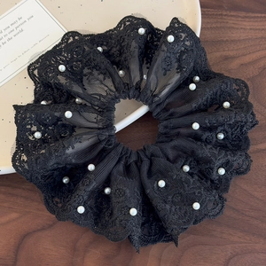 Gros plan d'un chouchou en dentelle noire orné de perles blanches de style vintage