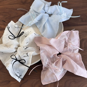 Three-piece set of lace-edged scrunchies with delicate ribbon bows in soft pastel tones
