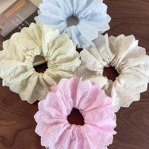 Set of four embroidered lace scrunchies in pastel colors on a dark wooden background