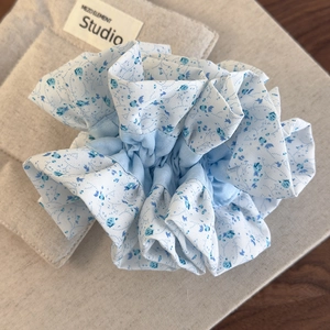 Gros plan du chouchou fleuri bleu clair avec plis en tissu souple et haute élasticité