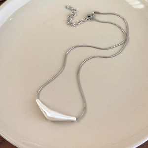 Detail of silver snake chain with white irregular pendant on a ceramic tray