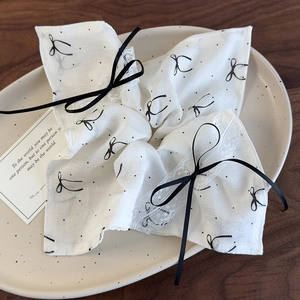 Detail of white lace scrunchie with black ribbon bow and floral patterns on ceramic tray