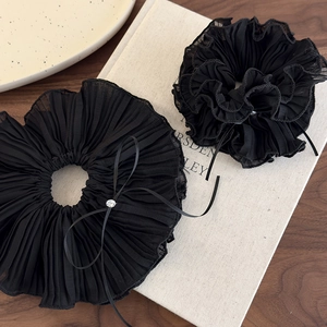 Close-up of pleated black chiffon scrunchies featuring ribbon bows and rhinestone details