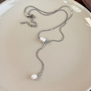 Macro view of silver snake chain necklace featuring a slider clasp and pearl drop