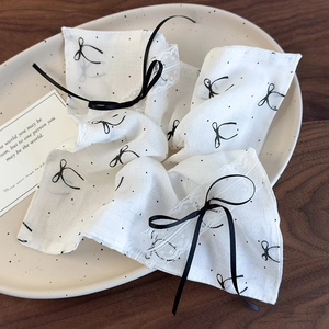 Detailed view of white lace handkerchief with black polka dots and ribbon bow decoration